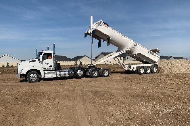 Sonny's end dump trailer unloading aggregate materials at job site